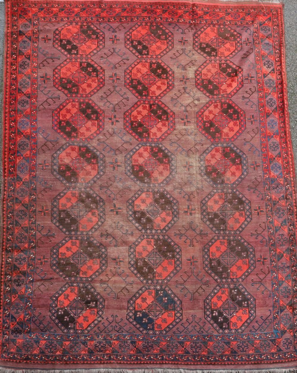 An Afghan aubergine and red ground carpet, with field of octagons and geometric motifs, 350 x 274cm